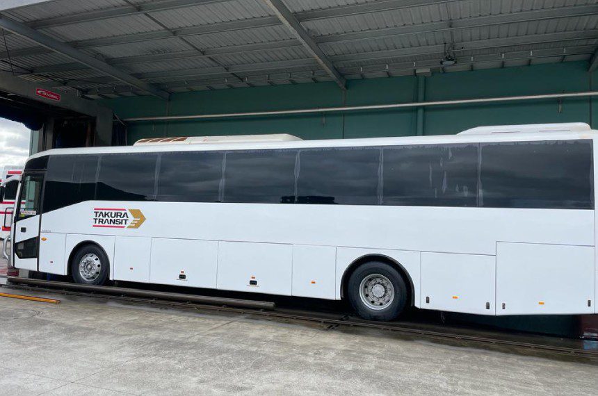 A white bus parked in front of a building.